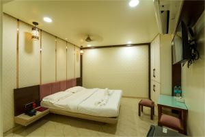 a room with a bed and a table and a television at La Hotel Metro near BKC in Mumbai