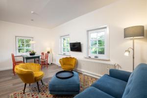 a living room with a blue couch and yellow chairs at Pförtnerhaus in Gartow