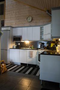 a kitchen with white cabinets and a clock on the wall at Koliwood A in Kolinkylä +14 photos