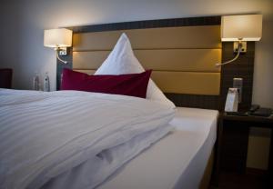 a bedroom with a white bed with a red pillow at Hotel Restaurant Passmann in Lüdenscheid