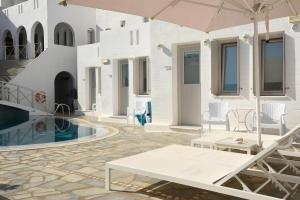 a patio with a table and an umbrella and a pool at Kanale's Rooms & Suites in Naousa