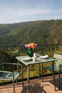 a table with a vase of flowers on a balcony at Cabana cu vedere spectaculoasa din pat - Apuseni Air Soare in Mătişeşti