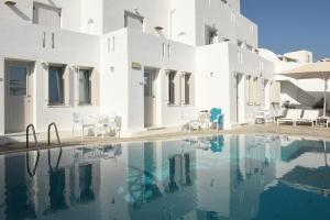 a swimming pool in front of a white building at Kanale's Rooms & Suites in Naousa