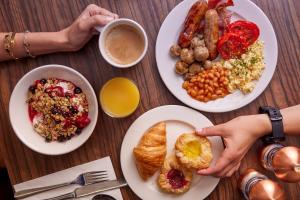 a table with plates of breakfast foods and a cup of coffee at Thistle London Hyde Park Kensington Gardens in London