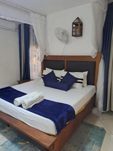 a bedroom with a bed with blue and white pillows at The Ocean Pearl in Diani Beach +27 photos