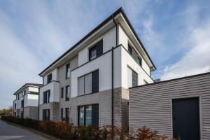 a white building with black windows on a street at Penthouse `Wolke 7` am See mit Sauna in Lembruch