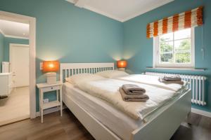 a bedroom with a bed with blue walls and a window at Pförtnerhaus in Gartow