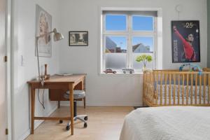 a bedroom with a crib and a desk and a window at Apartment in central Holstebro in Holstebro