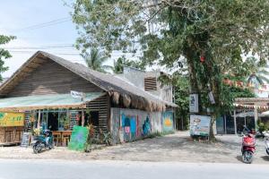 a small building with a thatched roof next to a street at Kalija in General Luna