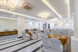 a banquet hall with tables and white chairs and chandeliers at S by Z Hotels, Baani Square in Gurgaon
