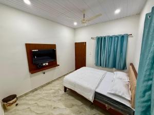 a bedroom with a bed and a flat screen tv at Kanasu Residency Malpe in Udupi +9 photos