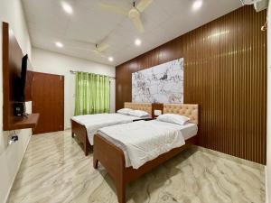 a bedroom with two beds and a television in it at Kanasu Residency Malpe in Udupi