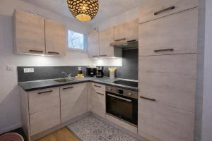 a kitchen with wooden cabinets and a sink and a chandelier at Appartement hyper Centre Rénové Terrasse & Parking in Tours