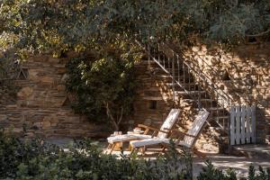 two chairs and a table in front of a brick wall at Seashore Villas Tinos in Tinos