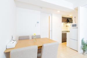a white kitchen with a wooden table and chairs at mks102 in Sapporo