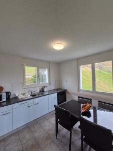 a kitchen with white cabinets and a table with a bowl of fruit at Ferienwohnung Suter in Seewen