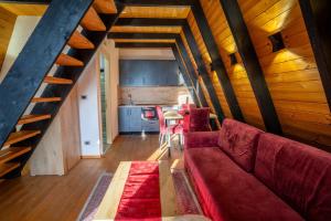 a living room with a red couch and a kitchen at Golden Cabins Gjinar by PikHost in Elbasan
