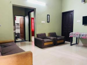 a living room with two couches and a tv at Clement homes in Kalpetta
