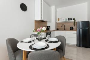 a white kitchen with a table and chairs and a refrigerator at Pino Resort Gdańsk by Solarento in Gdańsk