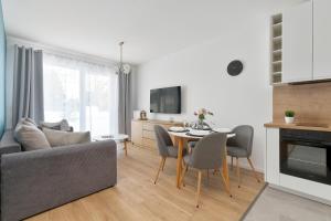 a living room with a couch and a table with chairs at Pino Resort Gdańsk by Solarento in Gdańsk