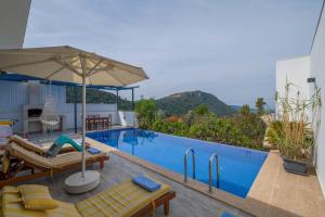 a swimming pool with an umbrella and chairs next to a pool at VillA Esin in Kaş