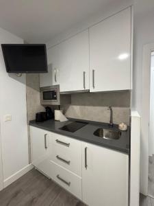 a kitchen with white cabinets and a sink at Hostal Los Rosales in Tejeda de Tiétar