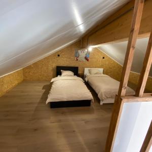 two beds in a attic bedroom with wooden floors at La maison d'à côté - Sart in Jalhay