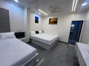 a room with two beds and a mirror in it at Hotel Tulsi in Aurangabad