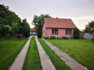 a pink house with a grassy yard next to a house at Little Village Loft in Káty +3 photos
