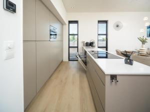 a kitchen with white cabinets and a wooden floor at Villa L-Meerzicht | 4 pers. in Workum