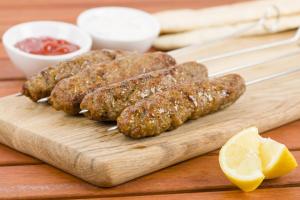 a wooden cutting board with three meatballs and a lemon at Hotel Asian Near Delhi Airport in New Delhi