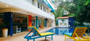two chairs and a pool in front of a house at goSTOPS PLUS Goa, Vagator in Old Goa