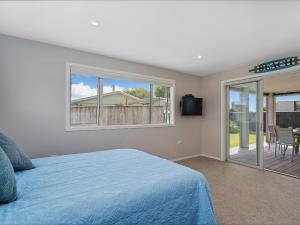 a bedroom with a bed and a view of a deck at Soleil Studio - Whangamata Self-contained Unit in Whangamata