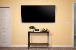 a flat screen tv on a wall with a table at The Williamsburg Haven in Williamsburg