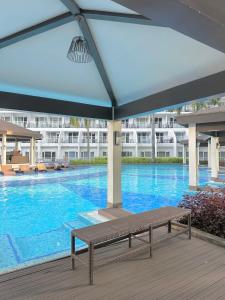 a large swimming pool with a bench in front of a building at Shell Residences MOA by Joseph in Manila