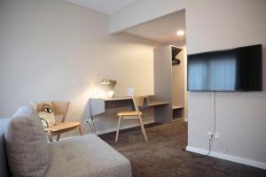a living room with a couch and a desk and a tv at Fjelsted Skov Hotel & Konference in Ejby