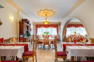 a dining room with tables and chairs and a chandelier at Hajdú Kastély Hotel in Hajdúszoboszló