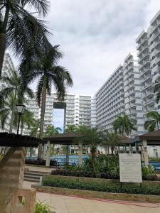 a large building with palm trees in front of it at Shell Residences MOA by Joseph in Manila