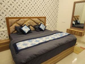 a bedroom with a bed with blue pillows and a mirror at pearl green's in Anandpur Sāhib