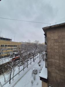 a snow covered street with trees and a building at Альтаир in Almaty