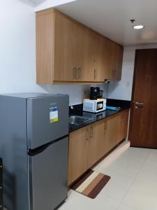 a kitchen with a stainless steel refrigerator and wooden cabinets at Shell Residences MOA by Joseph in Manila