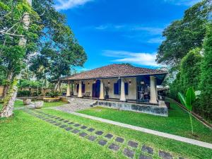a house with a garden and a grass yard at Heenatigala Walawwa - Free Shuttle to Our Private Beach in Talpe