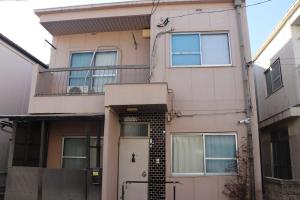 a pink house with a balcony and a door at 名古屋駅 中部国際空港近くの宿ひろし in Nagoya