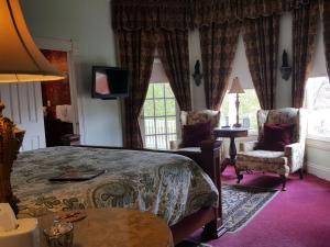 a bedroom with a bed and two chairs and a television at The Queen Anne Bed & Breakfast in Natchitoches