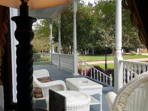a porch with white wicker chairs and a table at The Queen Anne Bed & Breakfast in Natchitoches