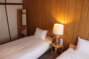 a small room with two beds and a lamp at 名古屋駅 中部国際空港近くの宿ひろし in Nagoya