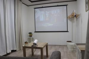 a white room with a projection screen and a table at 名古屋駅 中部国際空港近くの宿ひろし in Nagoya