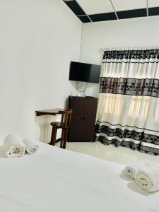 a bedroom with a bed and a chair and curtains at Miranda Villa in Ahungalla
