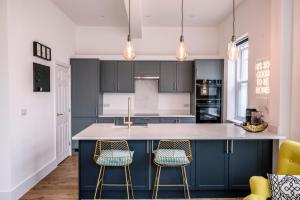 a kitchen with a blue island with two bar stools at The Leiston, High Street in Leiston