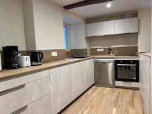 a kitchen with white cabinets and stainless steel appliances at Murat - La maison de la petite place in Murat +3 photos